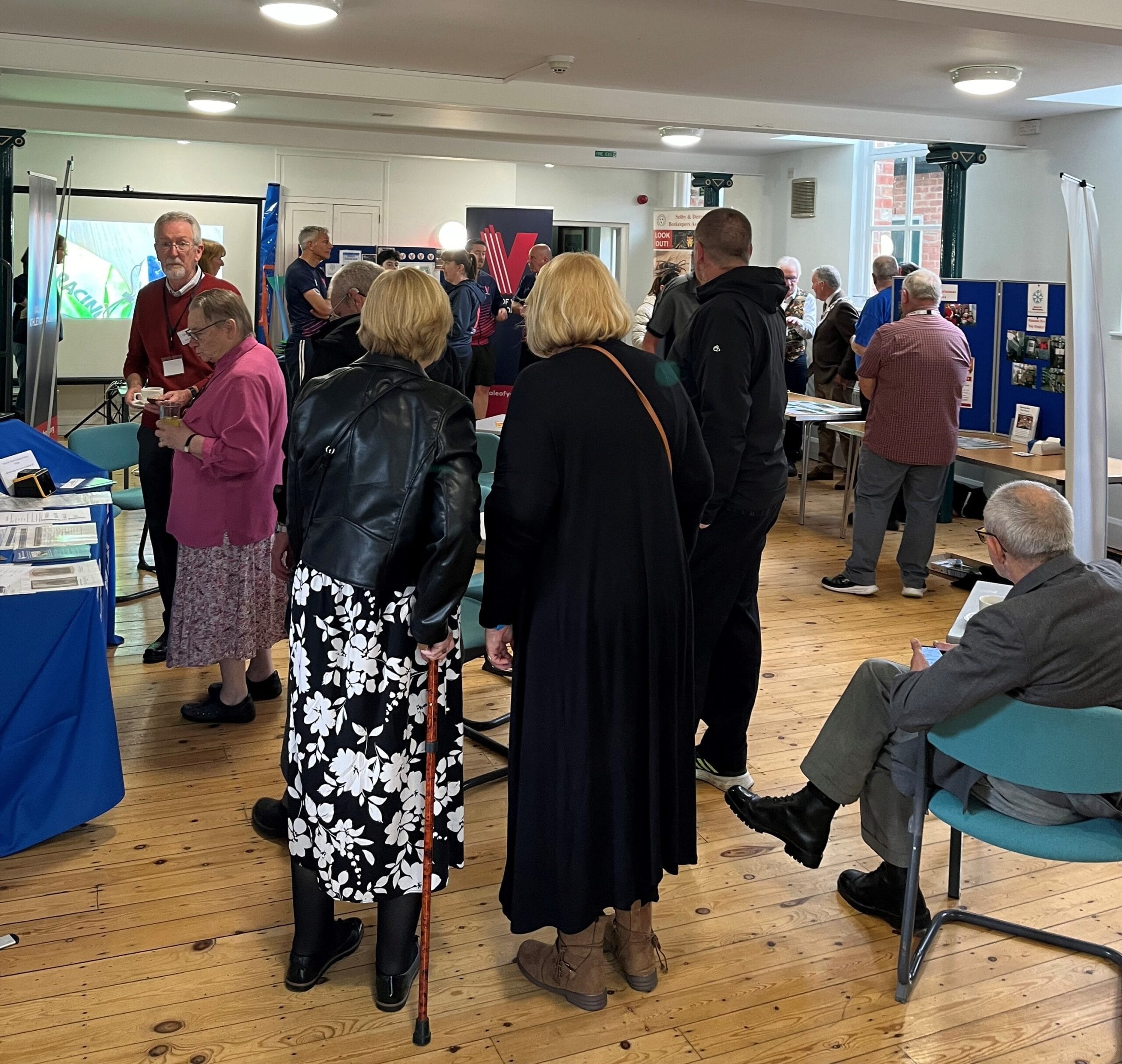 This is a photo showing residents attending the Annual Town Meeting. The photo shows residents viewing displays provided by various groups who were successful in receiving a grant from the Town Council in 2023