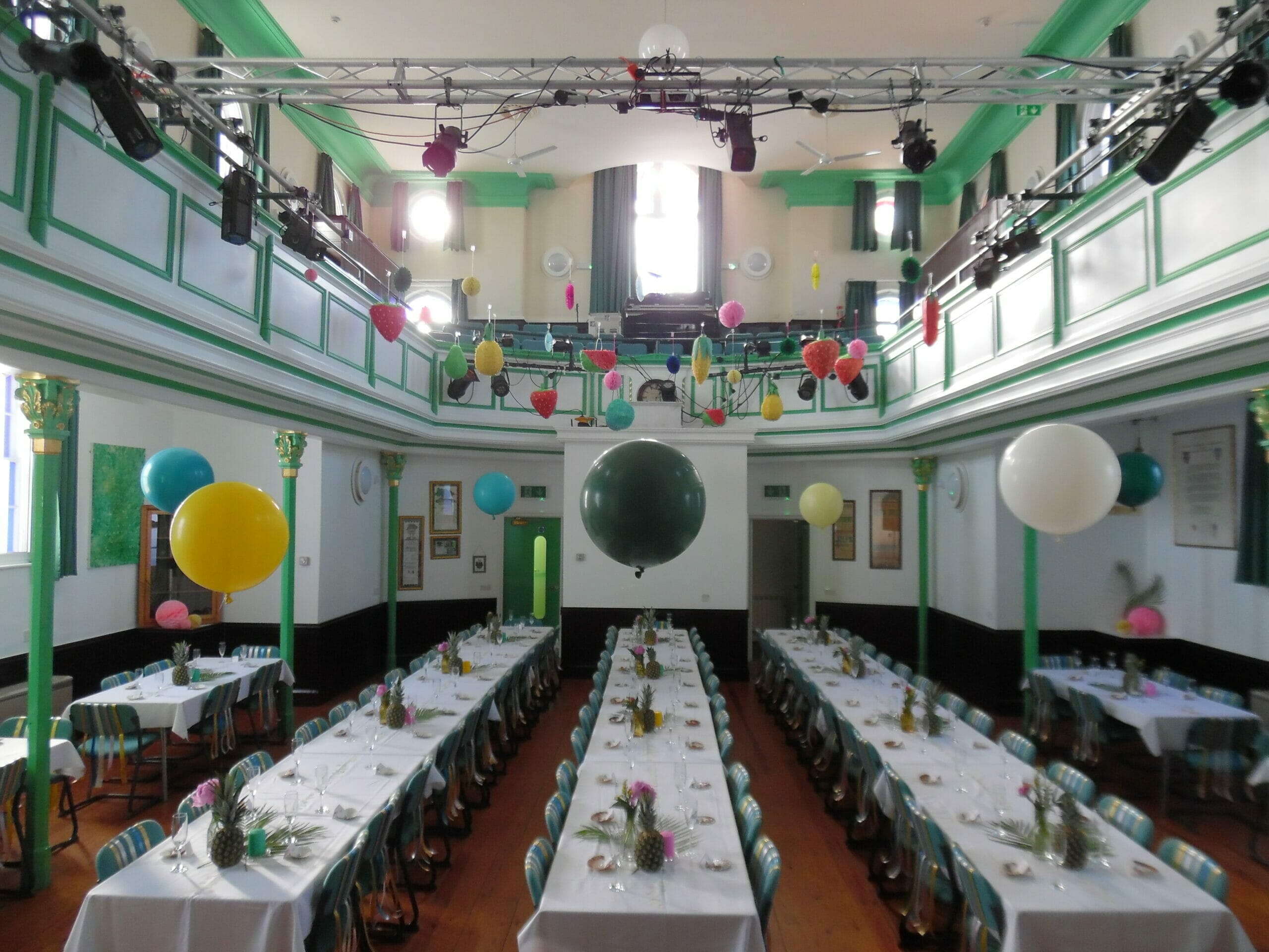 Photo shows a room layout with tressle tables and balloons
