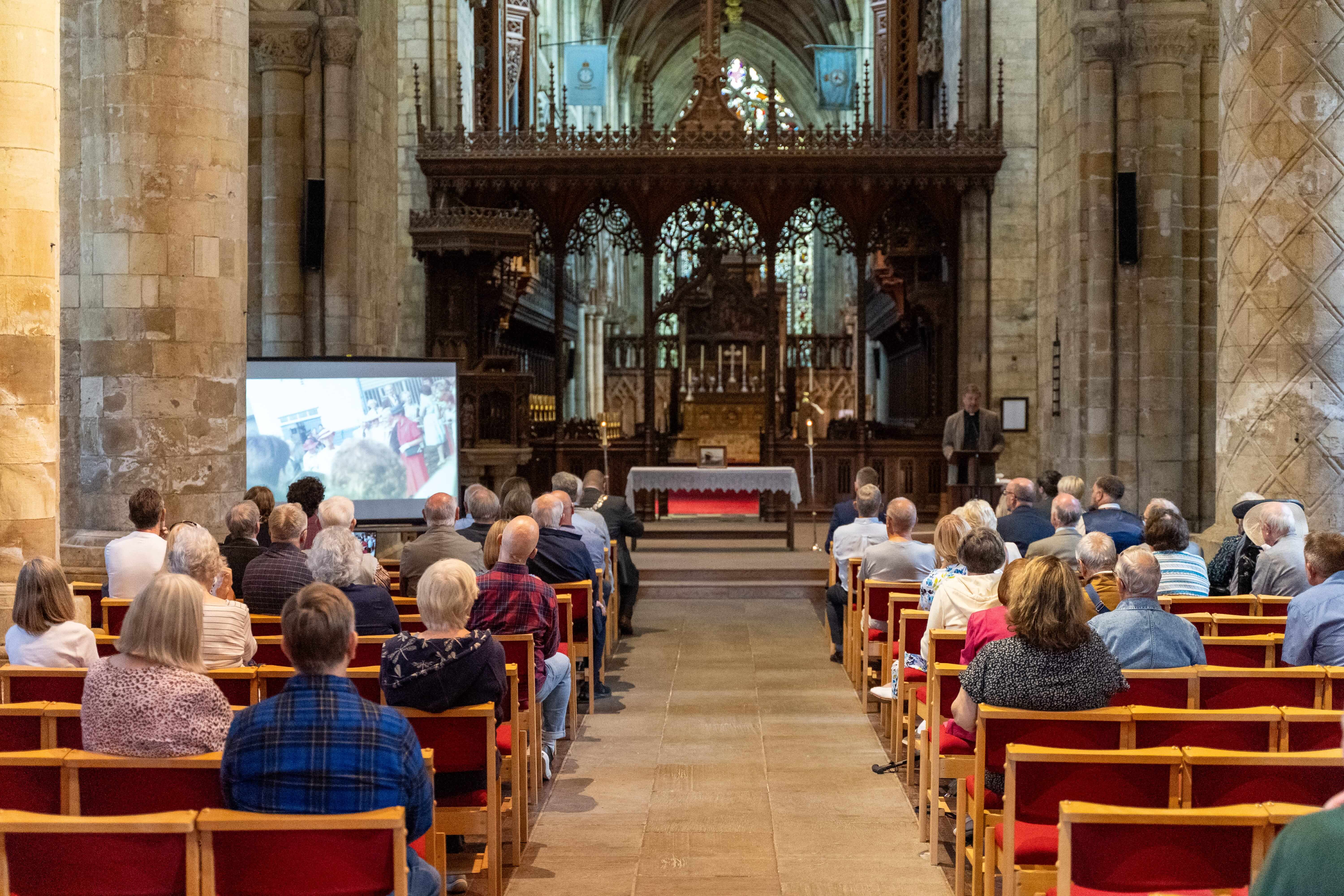 A gathering of people in Selby Abbey looking at a screen